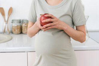 Kobieta w ciąży trzymająca jabłko
