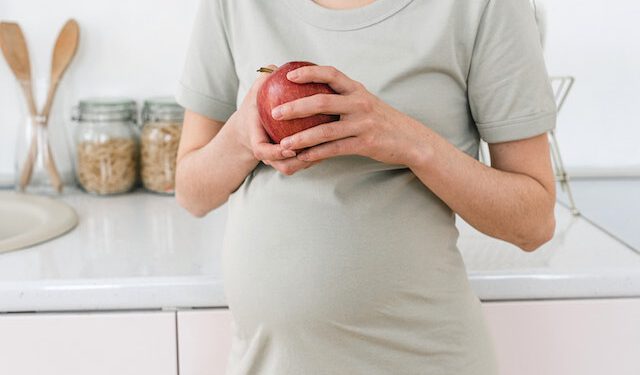 Kobieta w ciąży trzymająca jabłko
