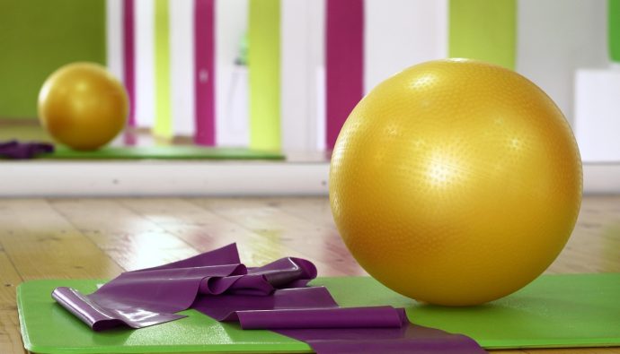 Piłka fitness, mata i taśmy do ćwiczeń w jasnej sali gimnastycznej